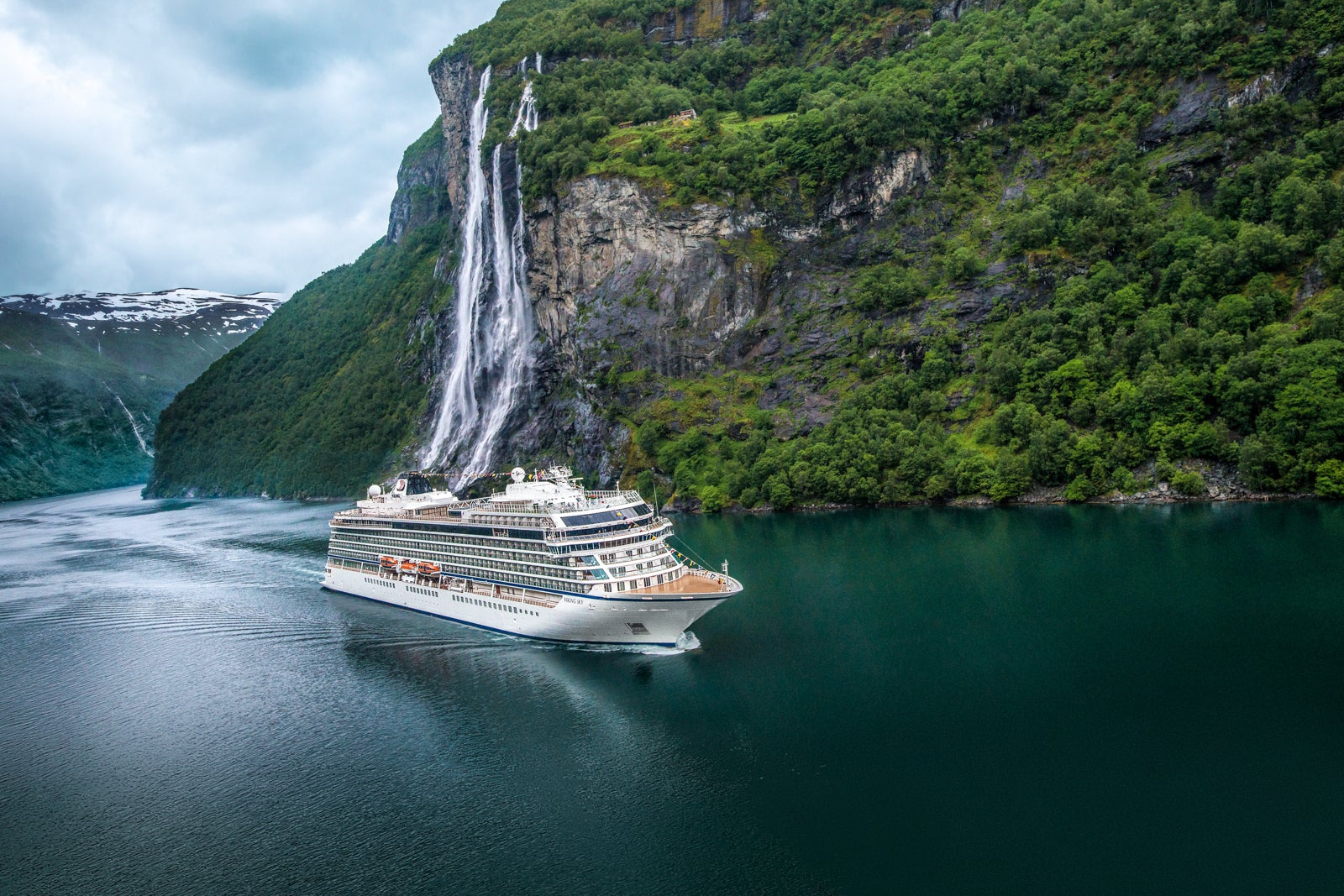 Viking Sky cruise ship sailing by Geiranger's Seven Sisters waterfall