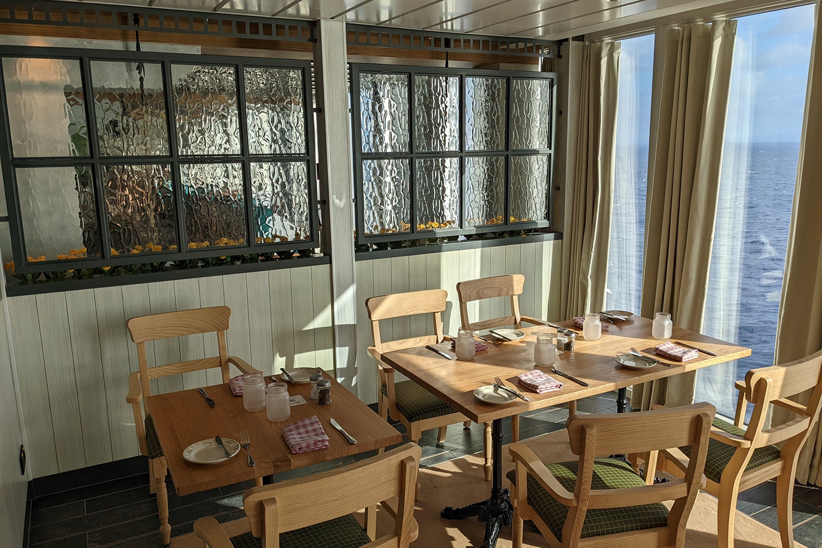 Wooden dining tables beneath windows, looking out to sea
