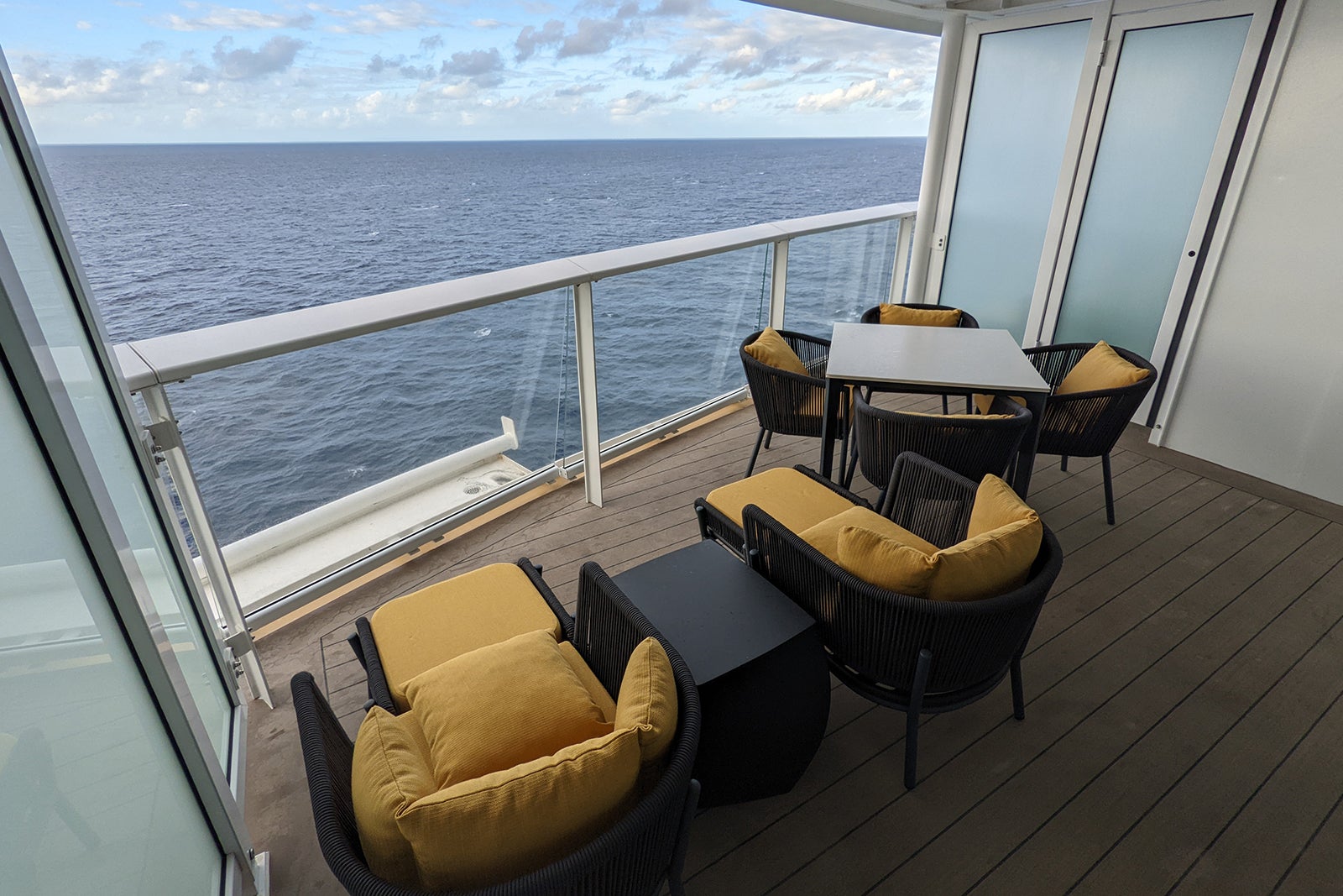 Cruise ship balcony with wicker furniture topped with yellow pillows