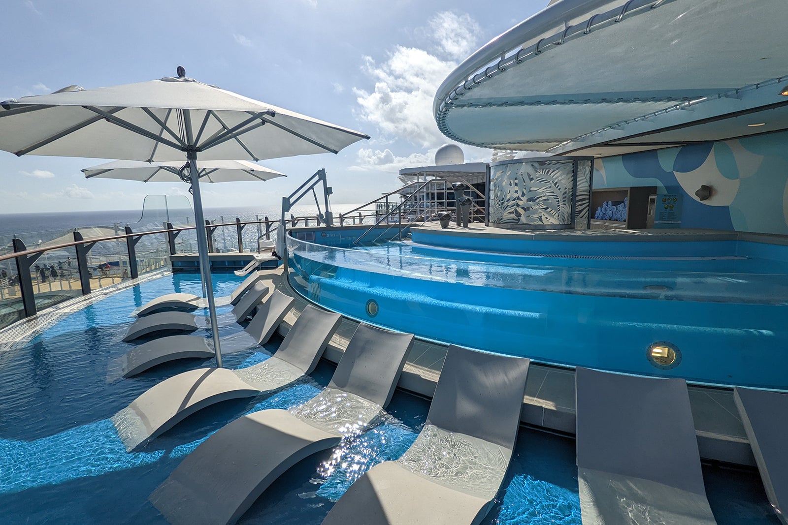 Lounge chairs in wading pool in front of large hot tub on a ship