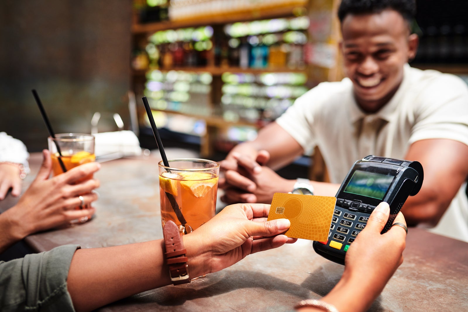 friends pay for drinks at a bar with a credit card