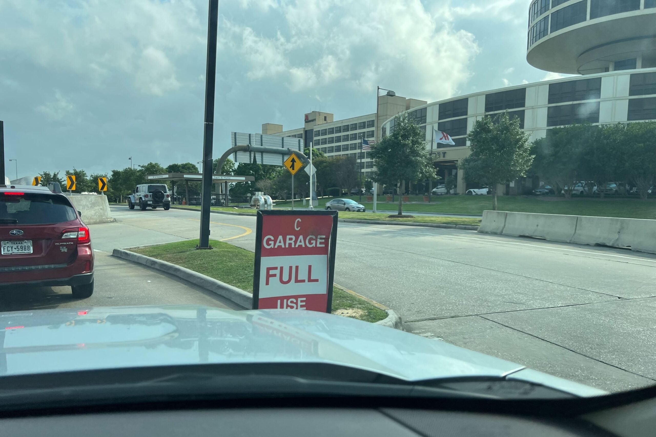 cars drive past a 'garage full' sign at an airport parking garage