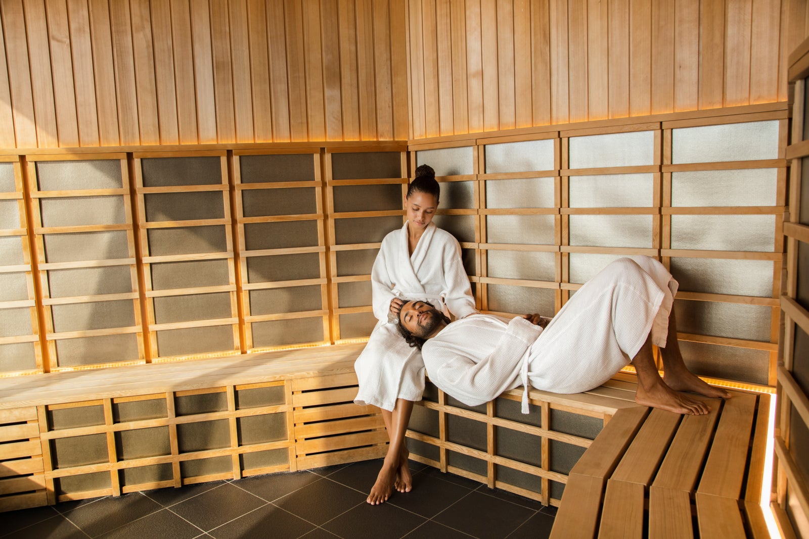 A couple in bath robes sitting in a sauna