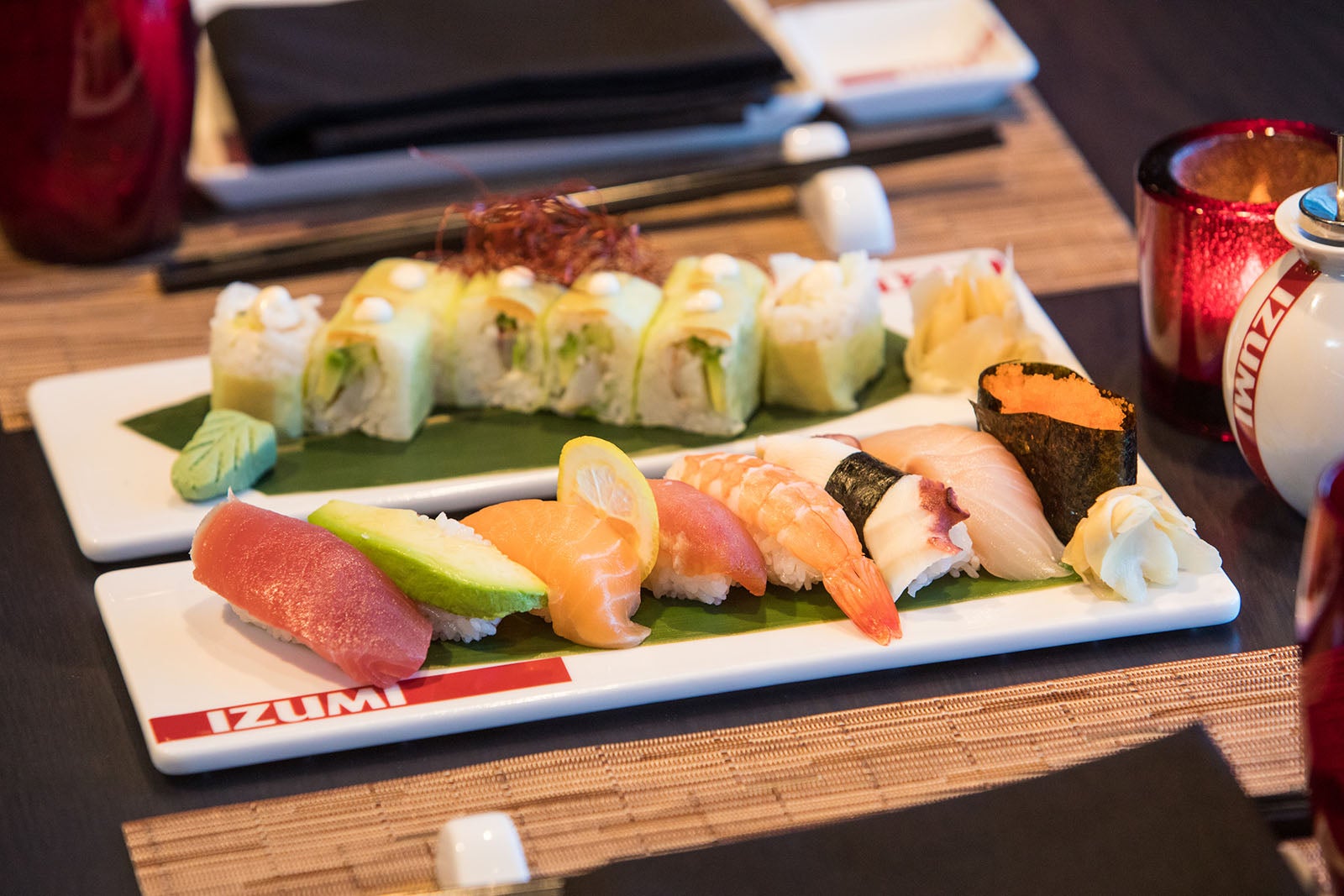 Two white retangular plates full of sushi and sashimi