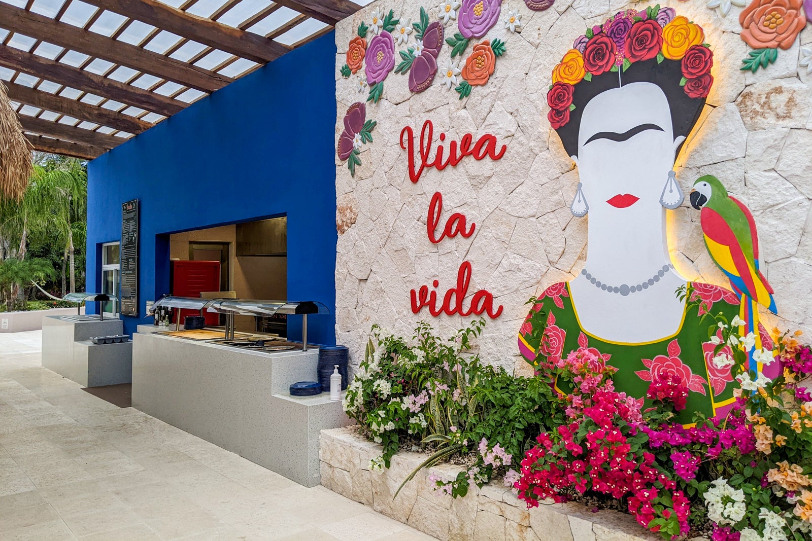 a food bar with "viva la vida" in giant letters on the wall next to a rendering of Frida Kahlo
