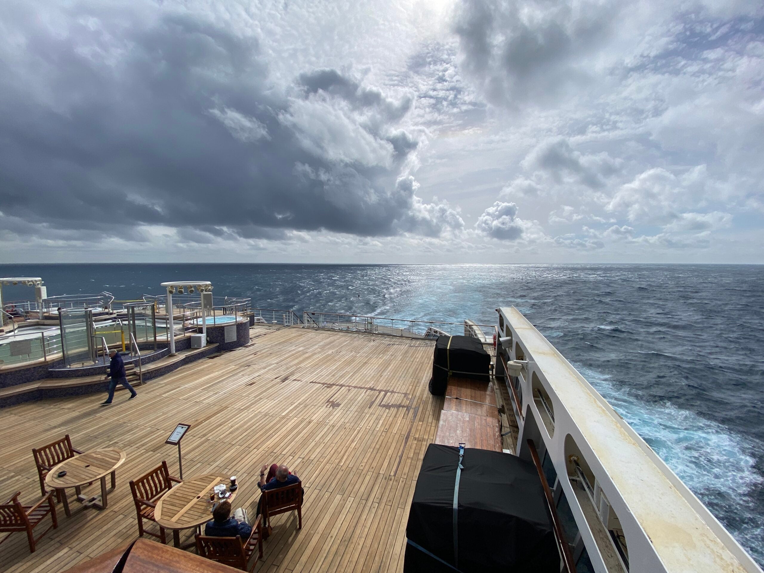 View of a cruise ship deck overlooking the wake and the open ocean and expansive sky on a transatlantic crossing