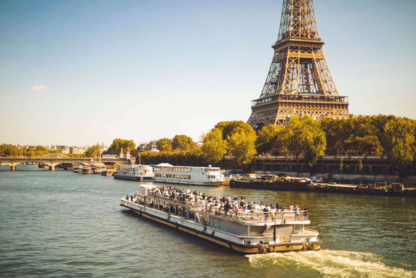 A river cruise boat sails along the Seine in front of the Eiffel Tower in Paris