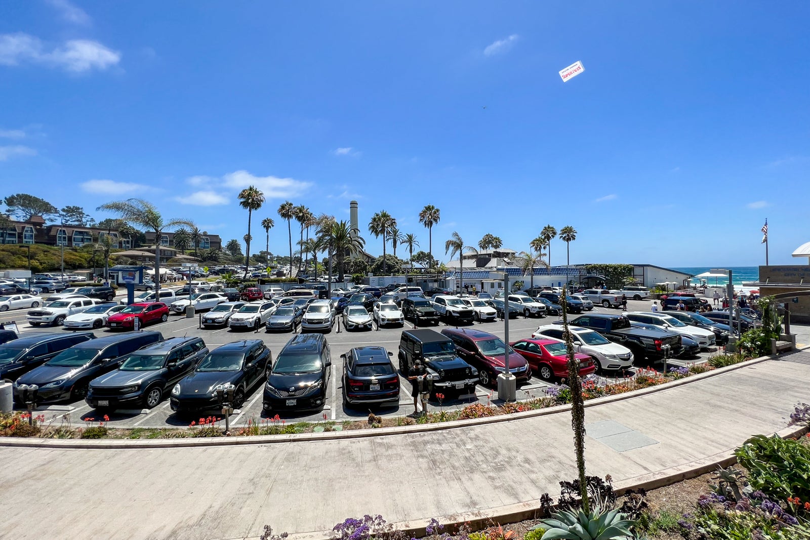 A parking lot filled with cars with palm trees in the background