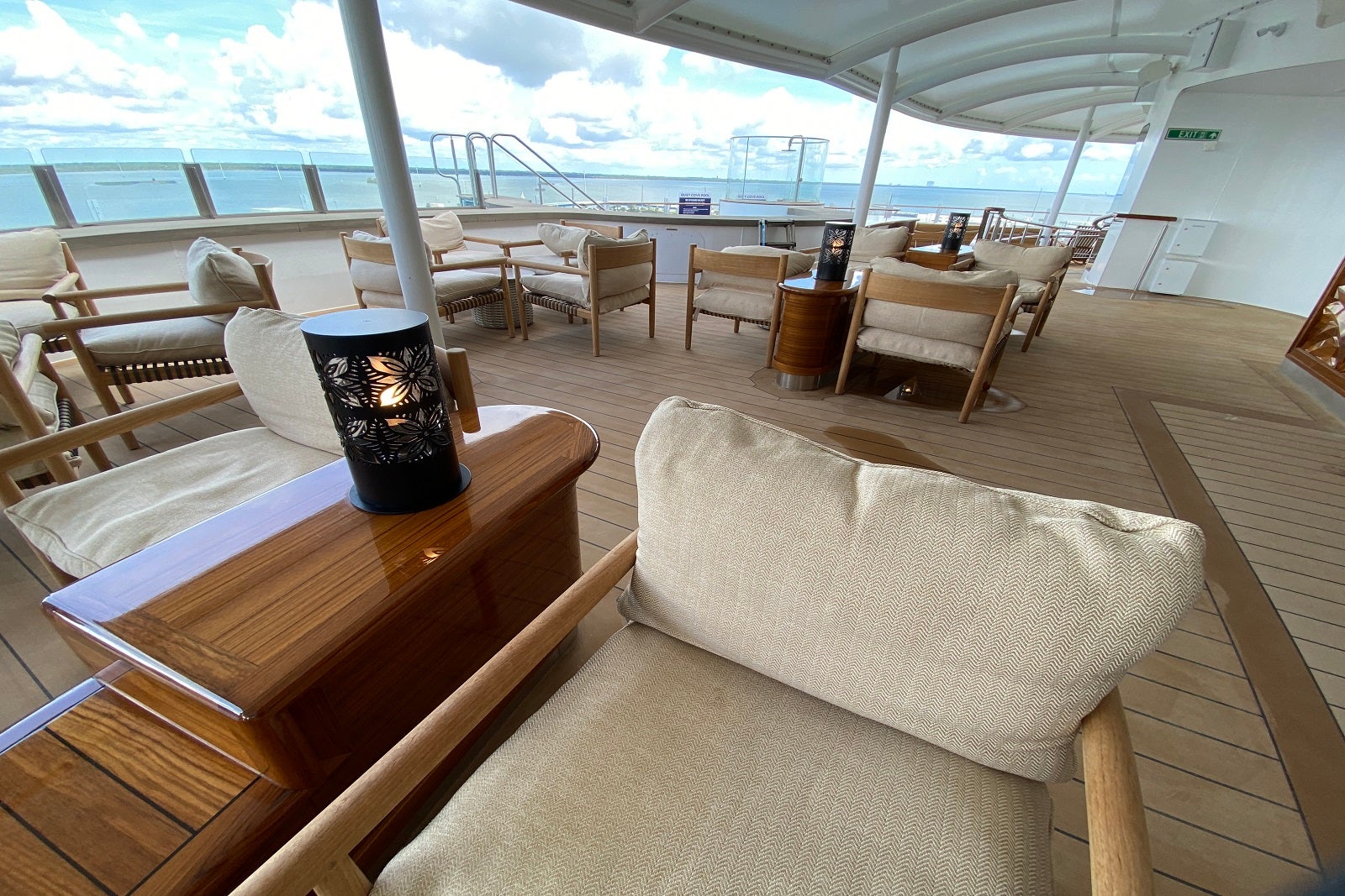 Neutral-colored tables and chairs on an open-air sun deck on a cruise ship