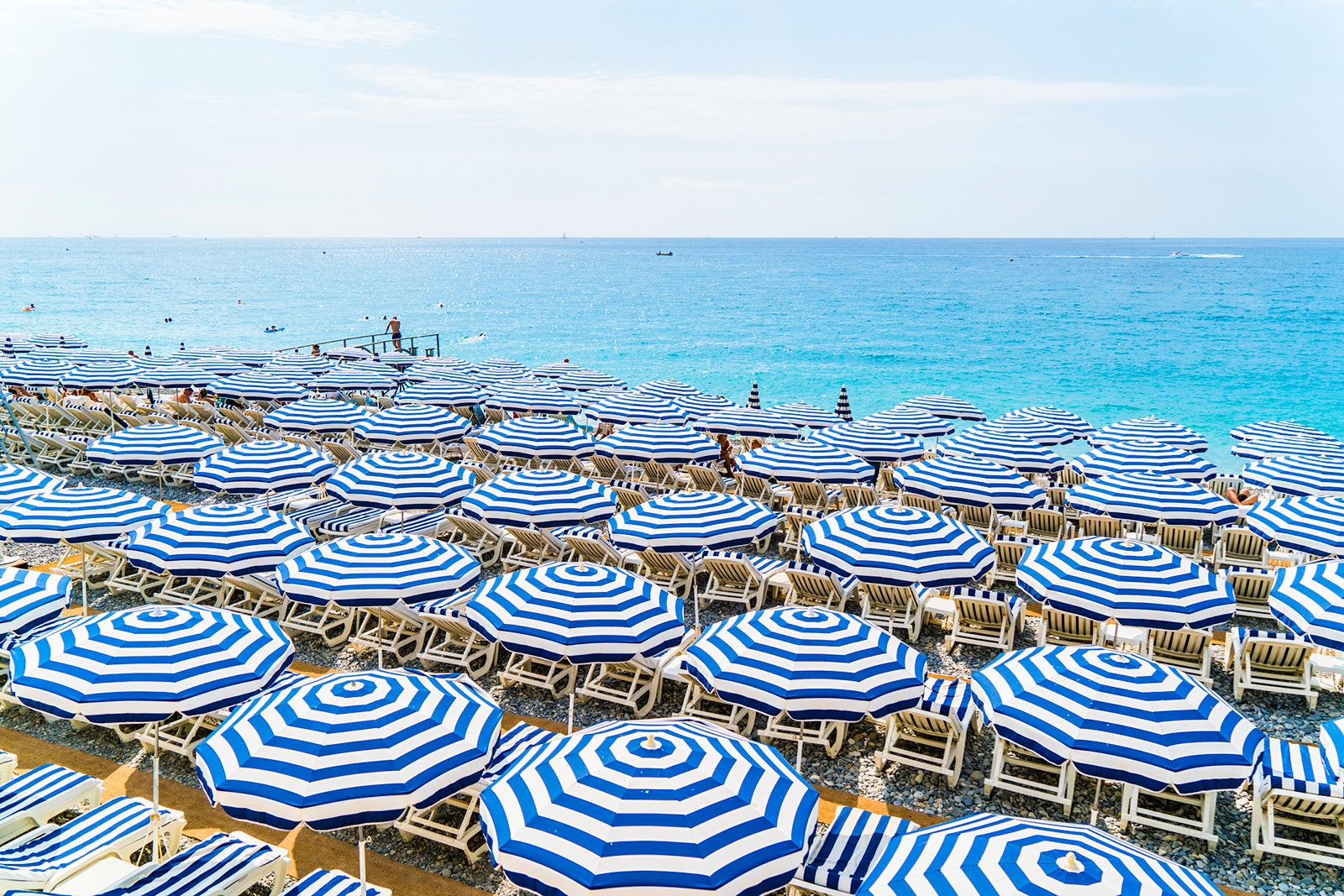 Rows of blue and white striped umbrellas line a beach