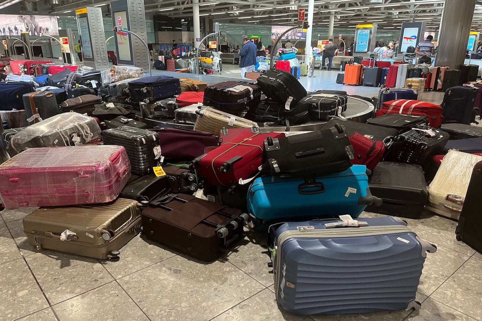 a disorganized pile of suitcases at baggage claim