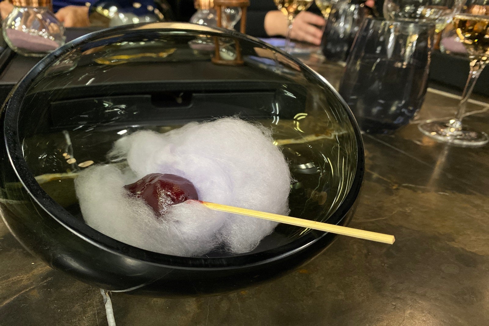 A bowl of cotton candy with a candied date lollipop on top