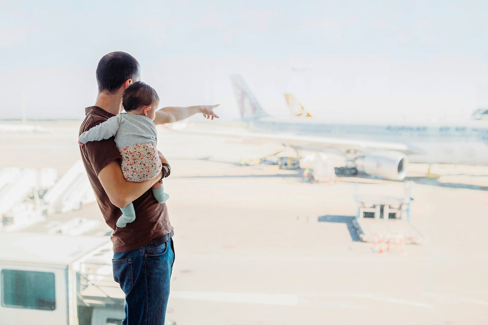 Man holds baby at airport and watches planes