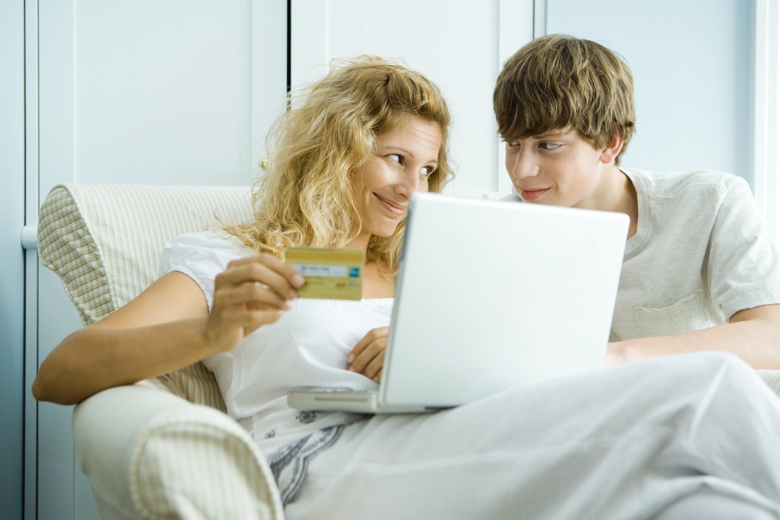 A mother and son look at a computer while holding a credit card