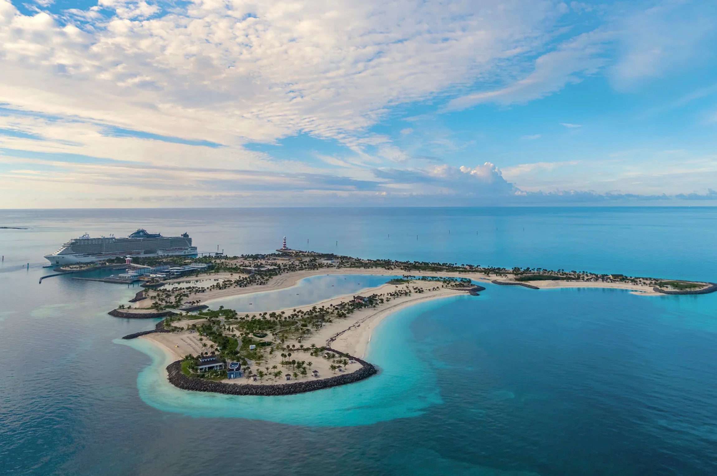 An aerial view of Ocean Cay, a private island in the Bahamas, surrounded by teal water and blue sky with white clouds overhead