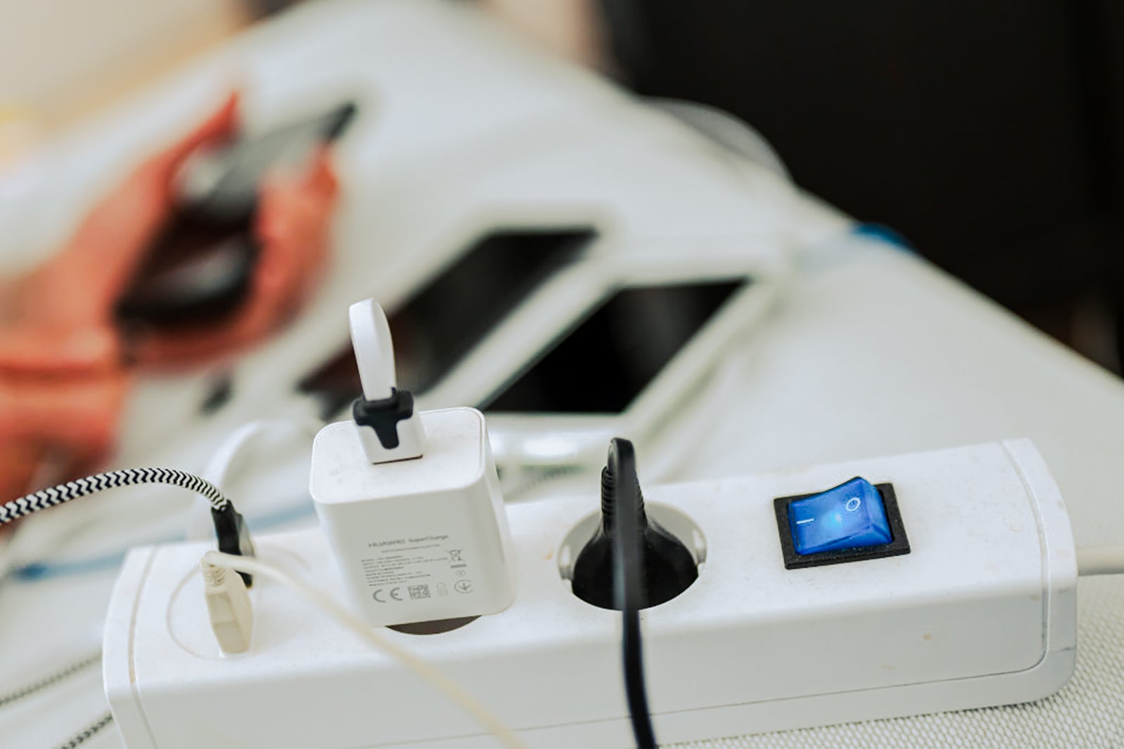 Close-up of a power strip with several electronics plugged into the outlets