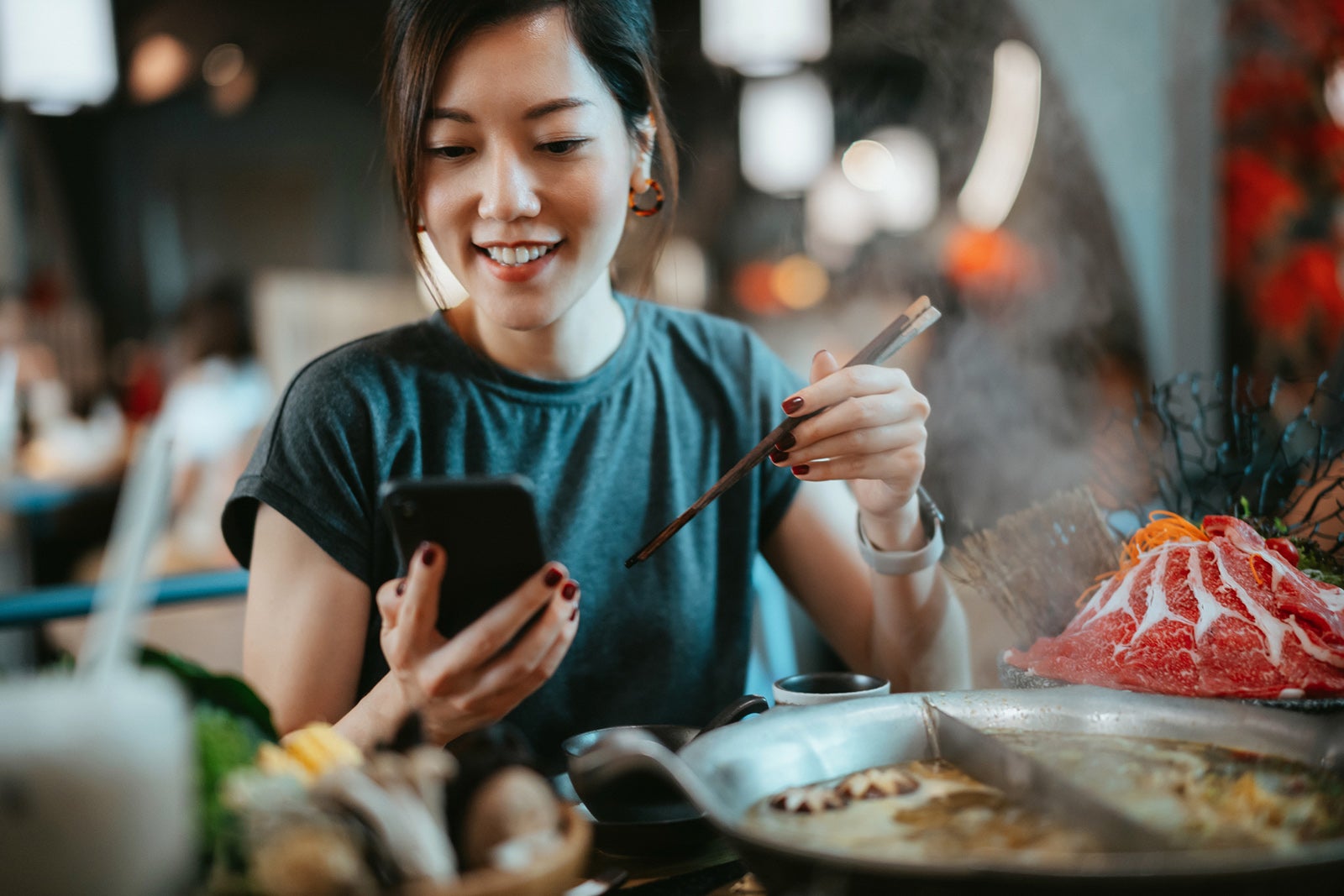 woman eating with chopsticks in restaurant