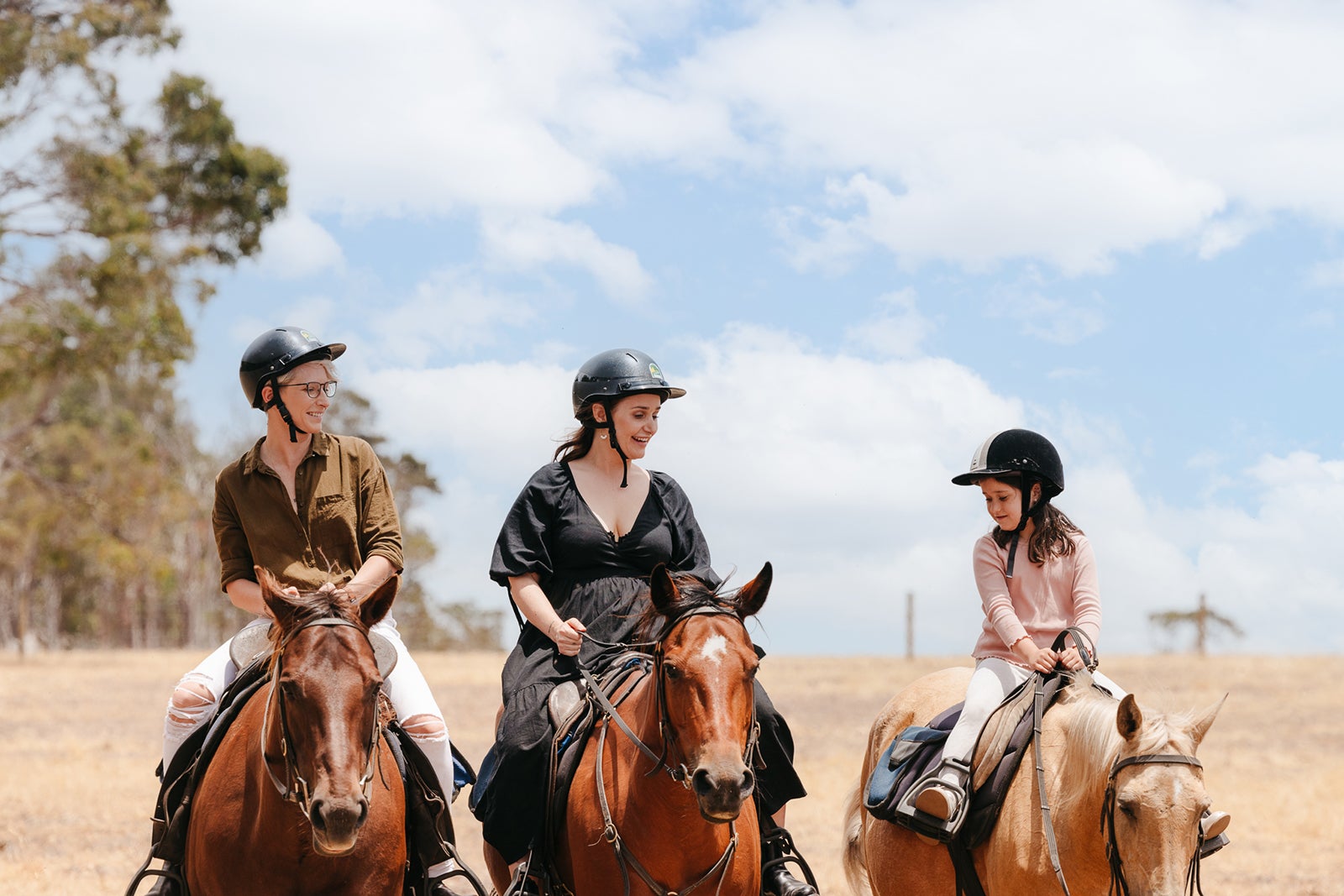 Two moms and a daughter riding horses on a tour