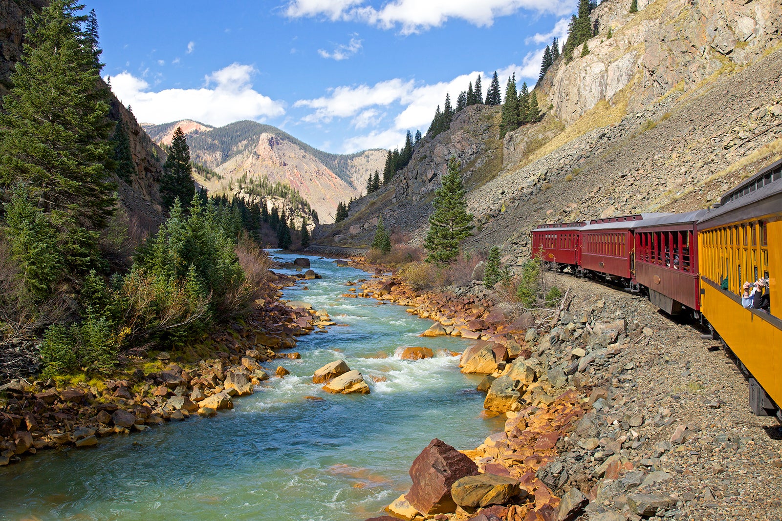 train running alongside stream in Rocky Mountains