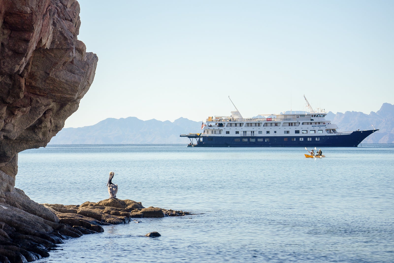 A cruise ship sailing into the frame next to a rock formation