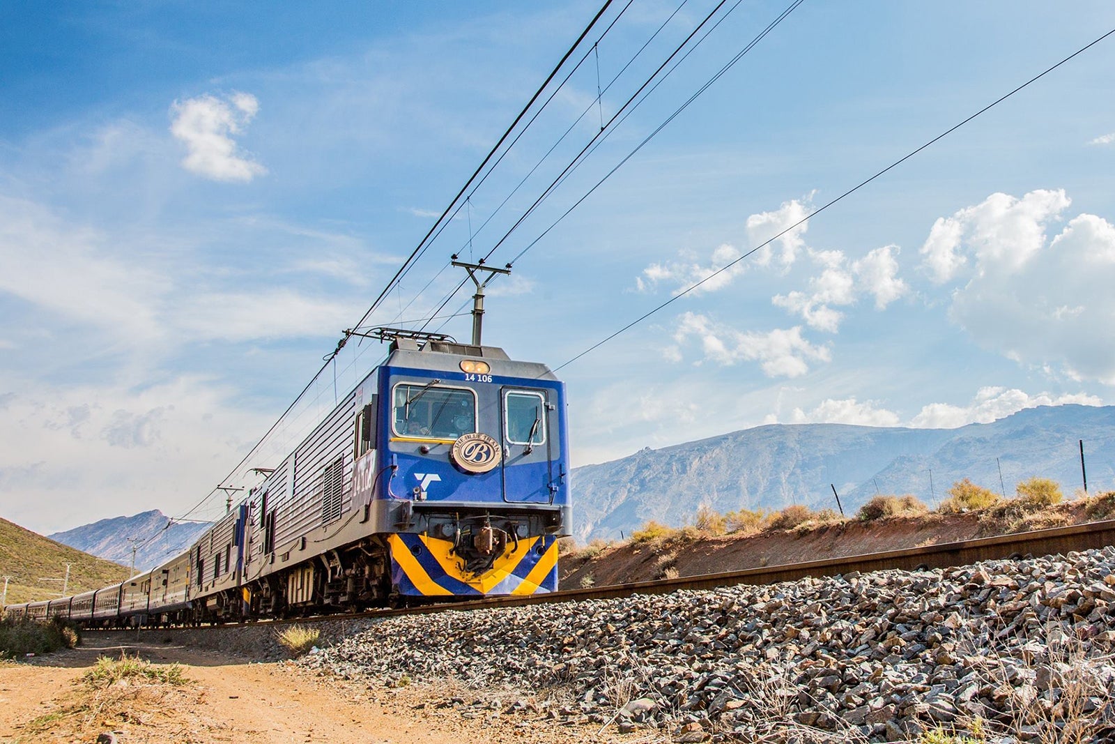 Blue Train on track with mountains in background