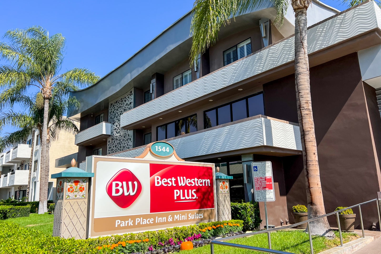 A red Best Western Plus sign in front of a brown hotel building