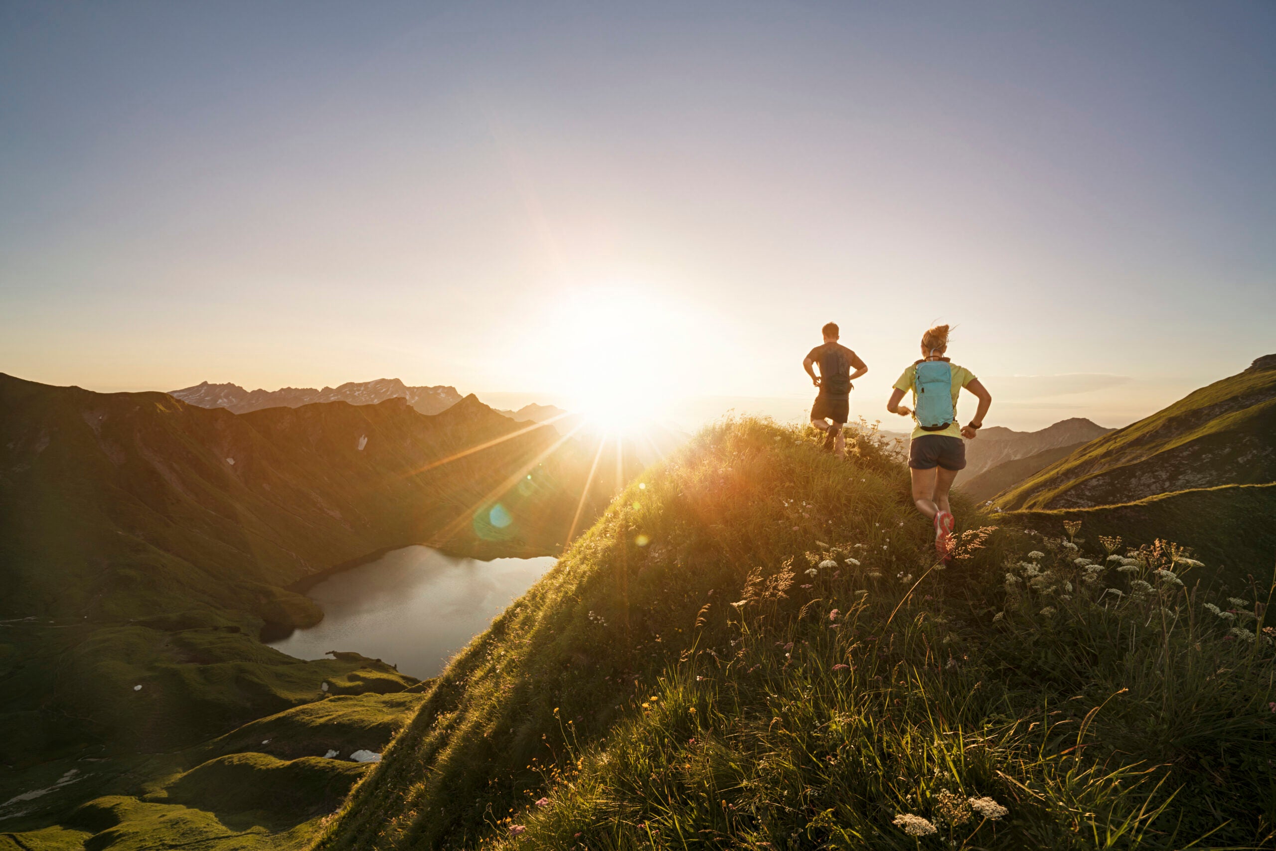 Germany, Allgaeu Alps, man and woman running on mountain trail.