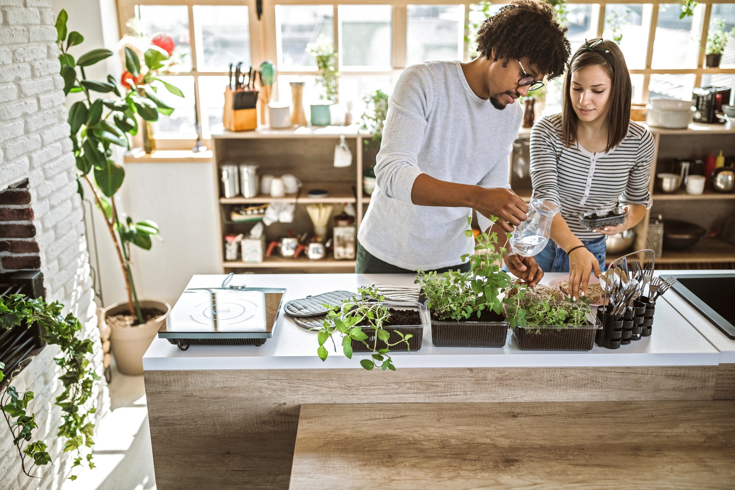 couple taking care of kitchen herbs.