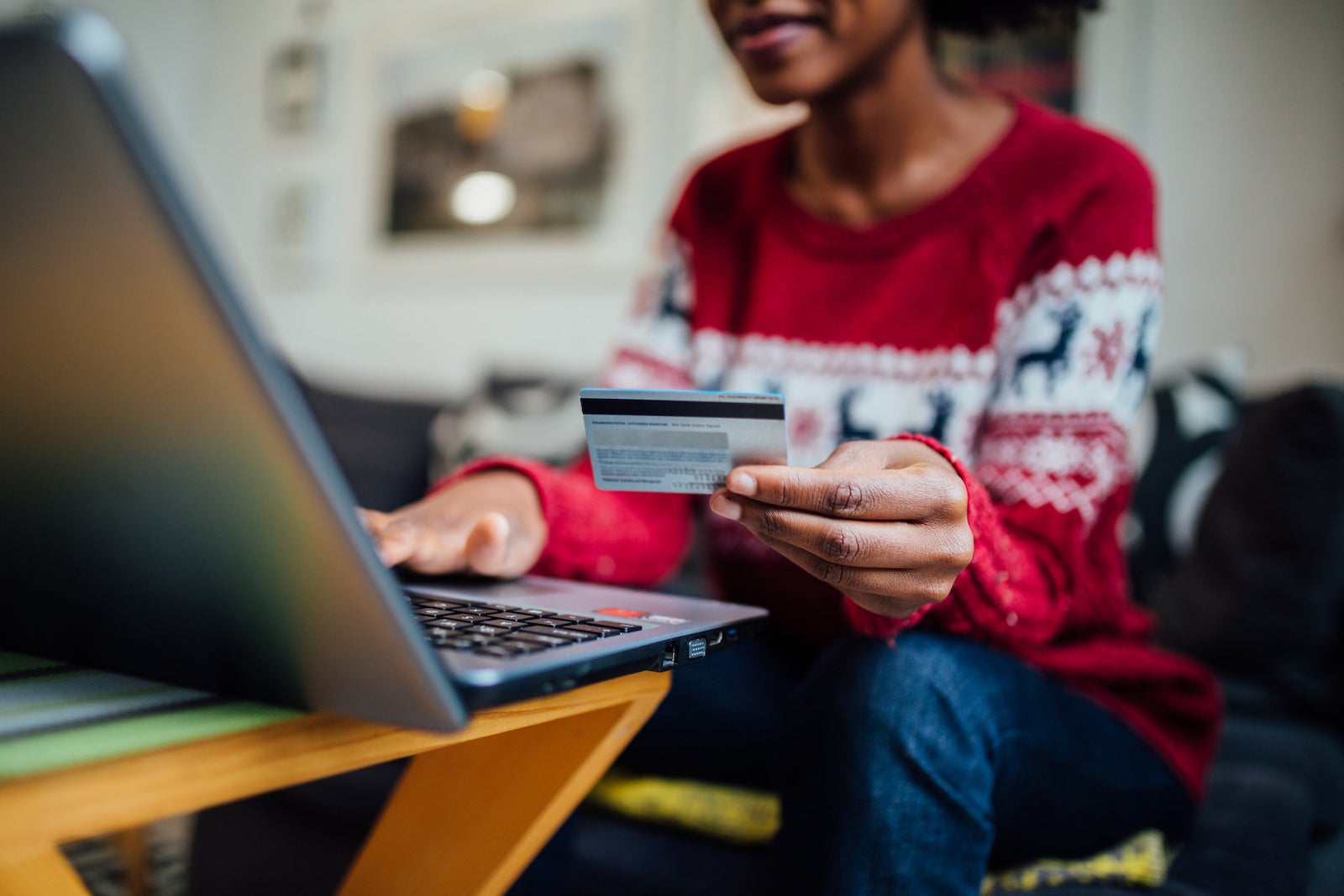 Person next to a laptop holding a credit card