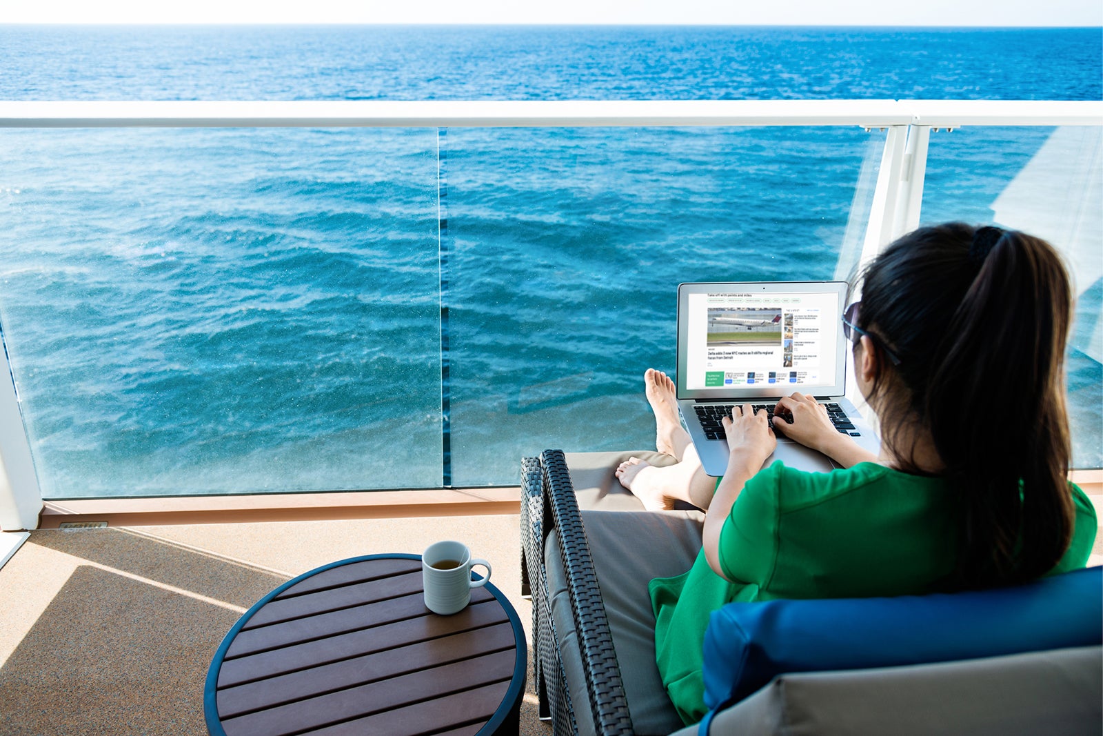 Woman using laptop on cruise-ship balcony.