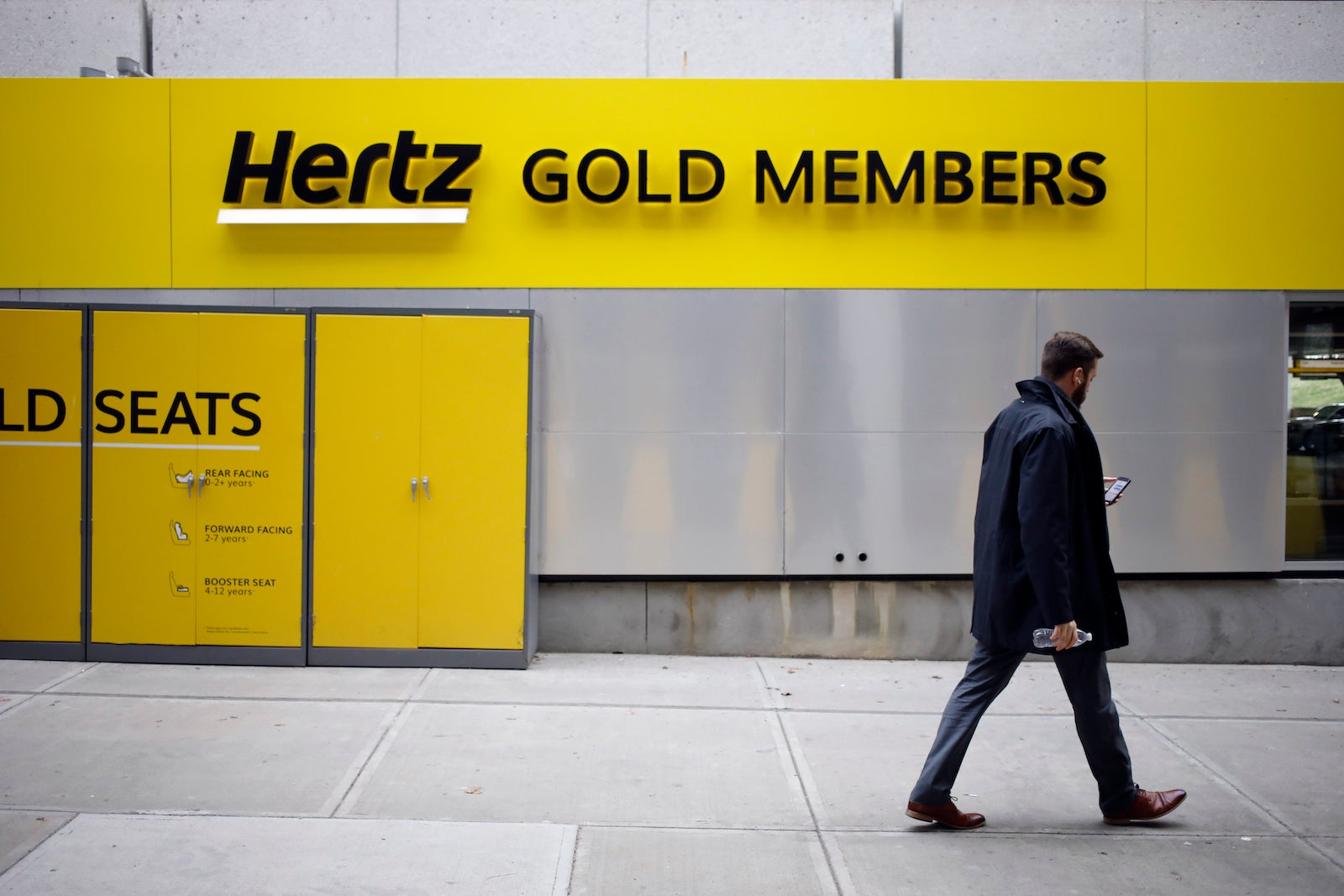 man walking past Hertz Gold Members sign