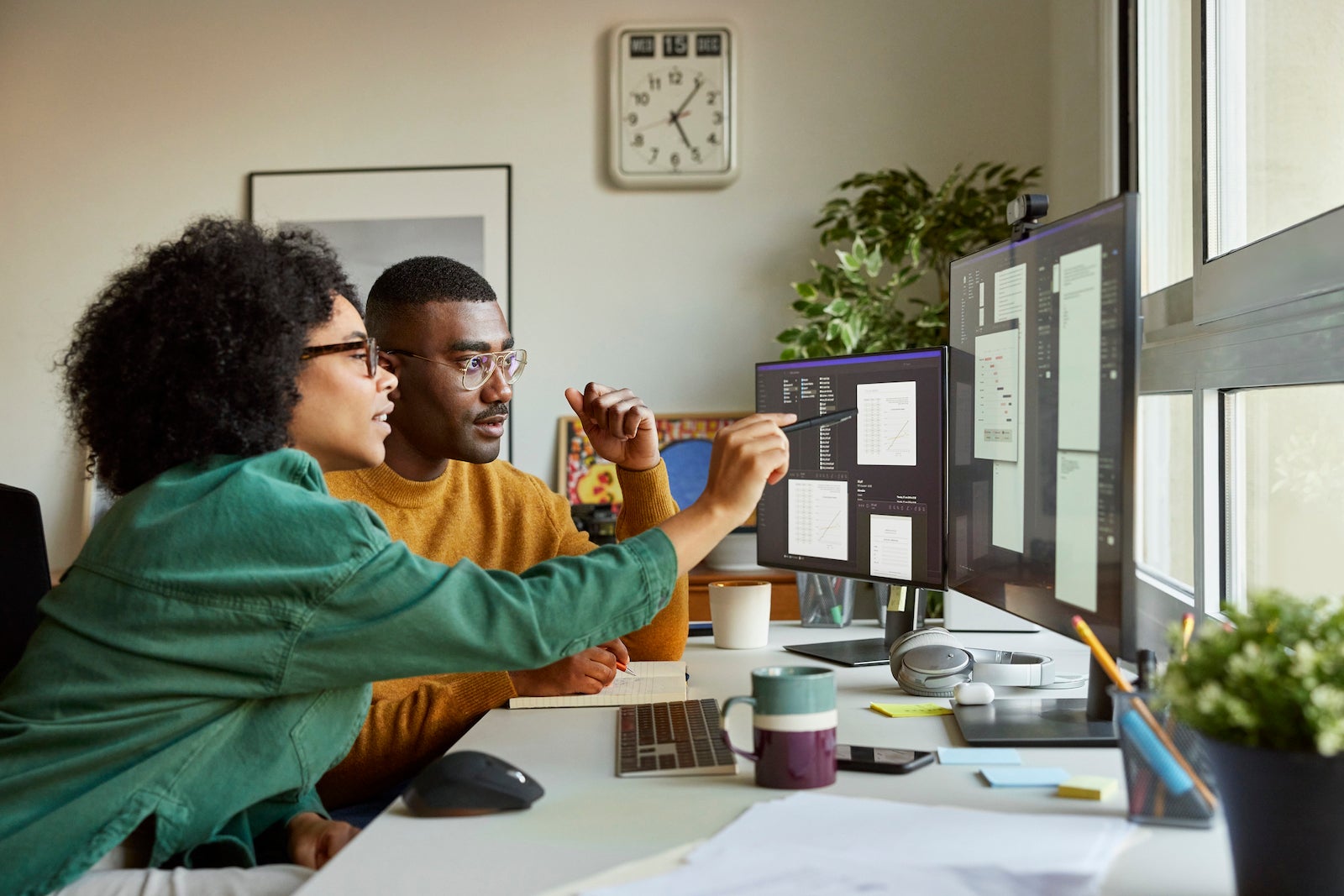 two business partners look at reports on a computer screen