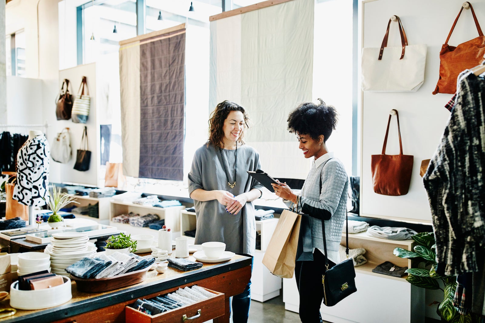 two employees in a clothing store look at an iPad together