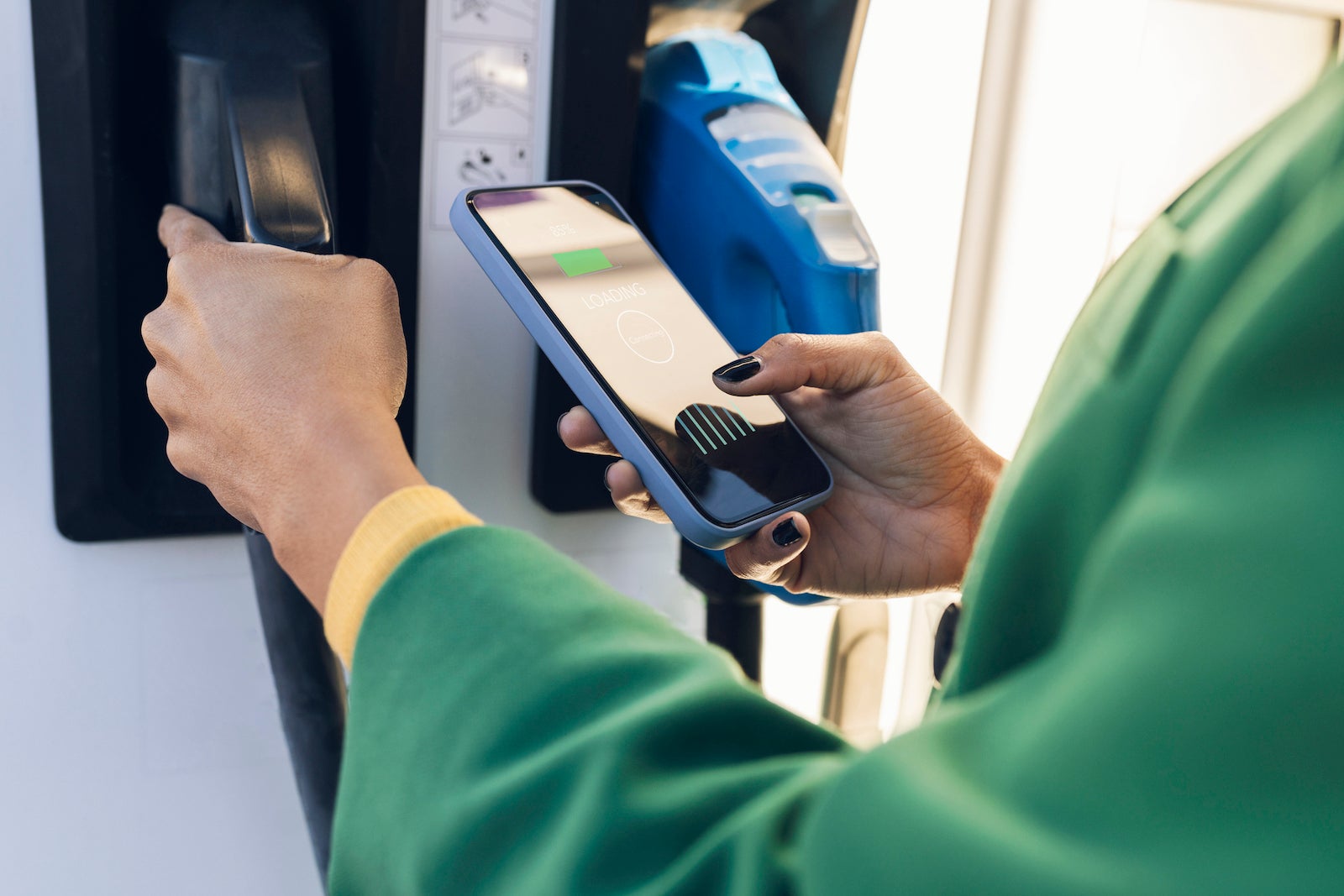 Commuter scanning QR code on mobile phone at gas station
