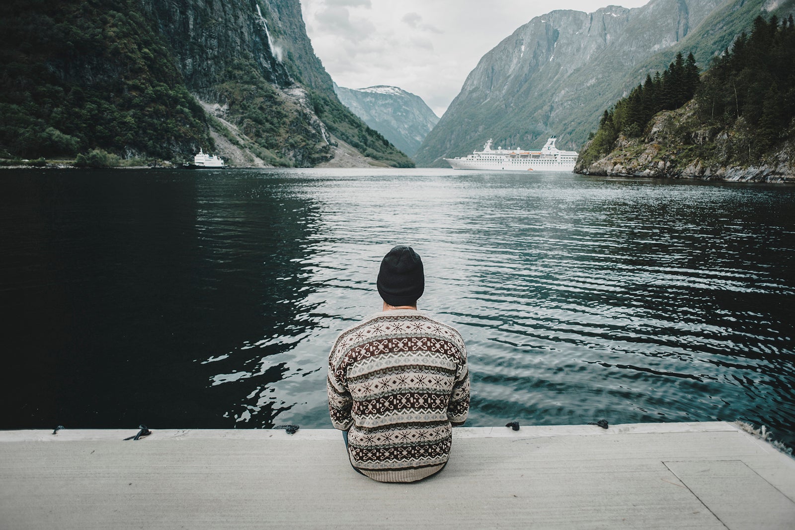 person sitting by water and mountains