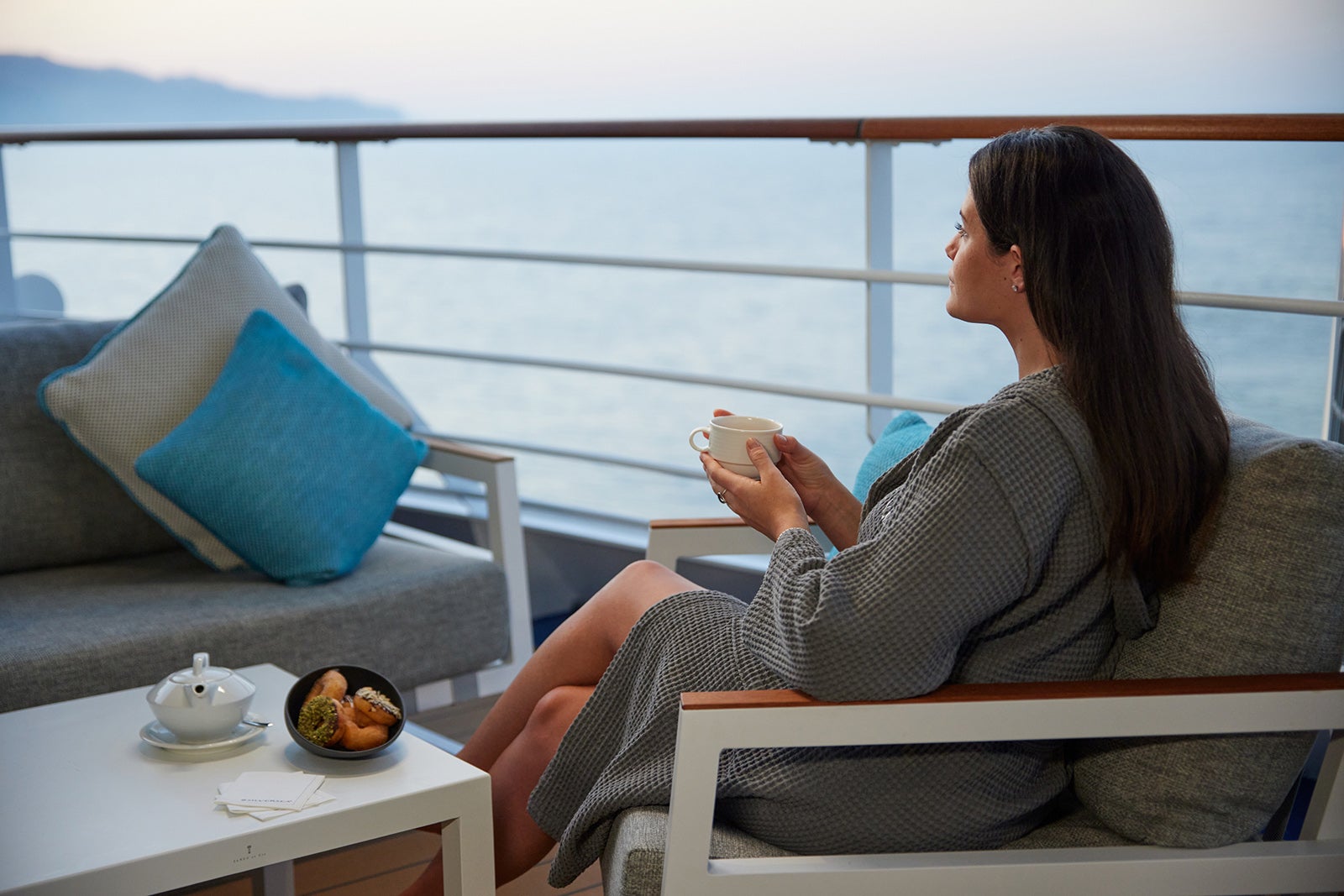 Woman in robe on deck drinking tea