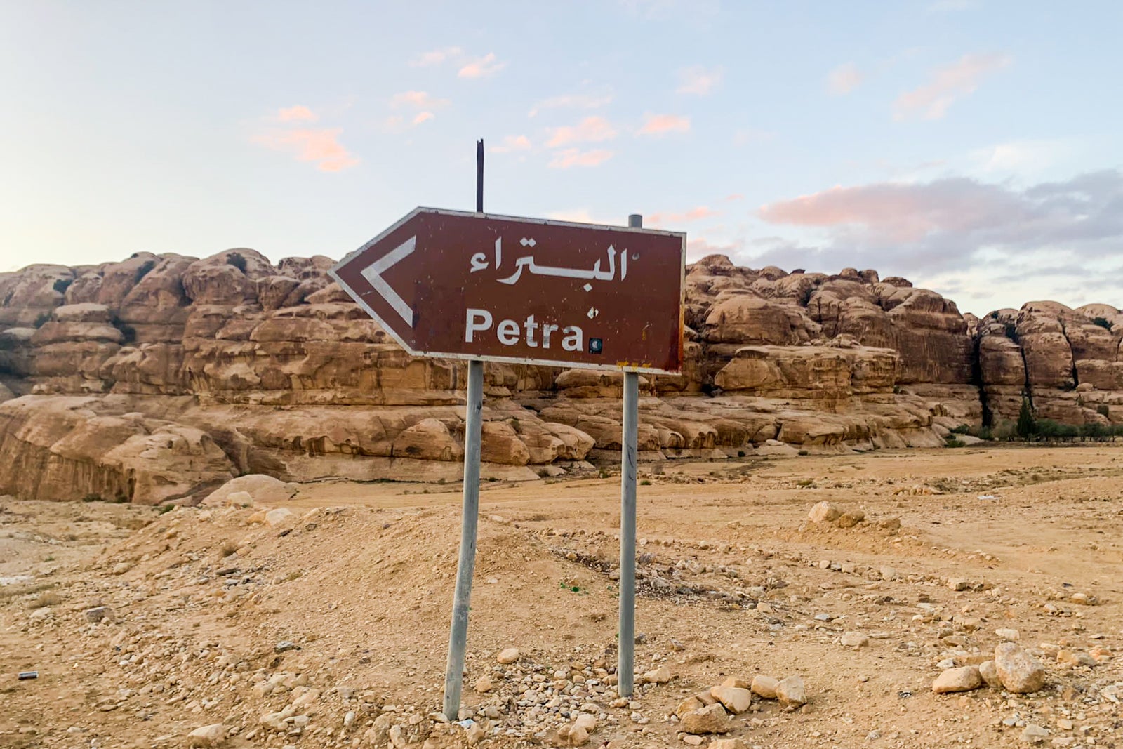 a sign in the desert indicates a left turn to drive toward Petra