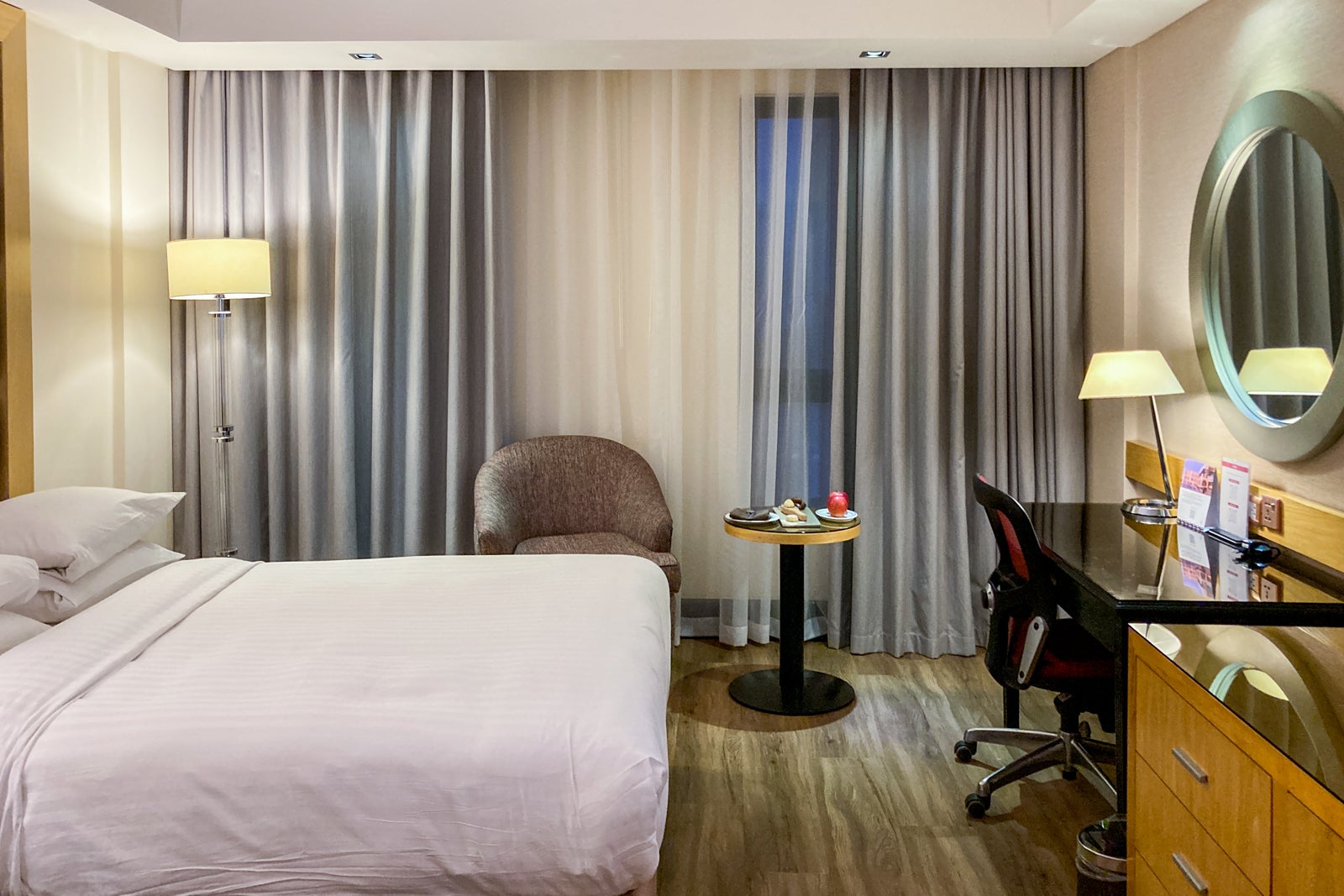 the interior of a hotel room with beds, chairs and a working desk