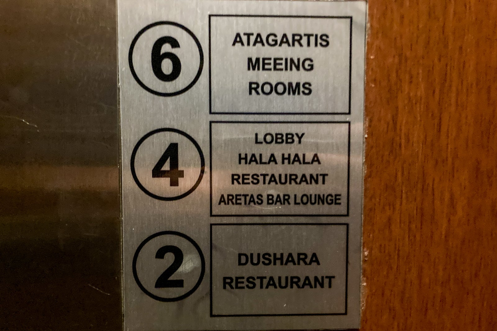 signage indicating what floor to go to for various parts of a hotel, posted next to an elevator