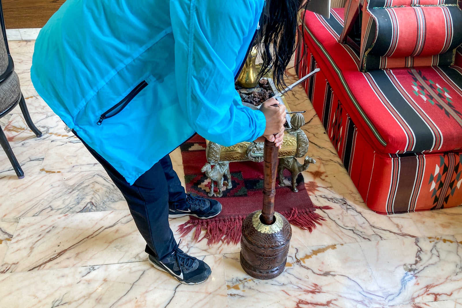 a person smashes coffee with a stick to prepare for roasting