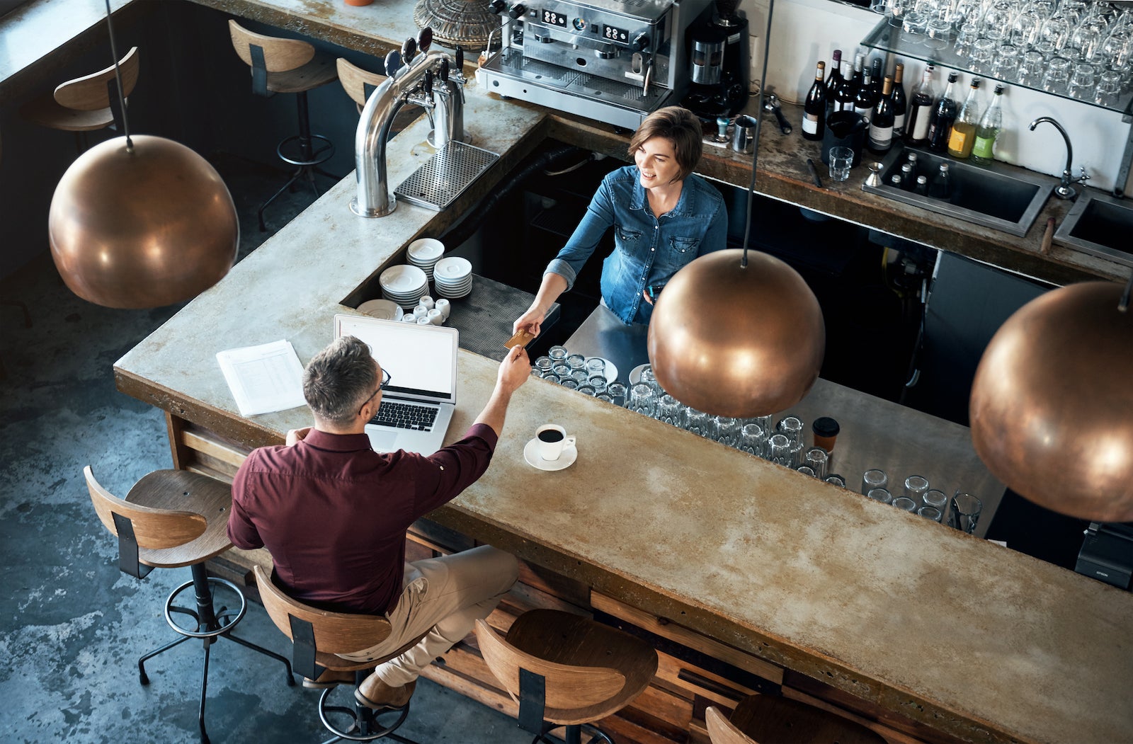 overhead view of a customer at a cafe paying by credit card