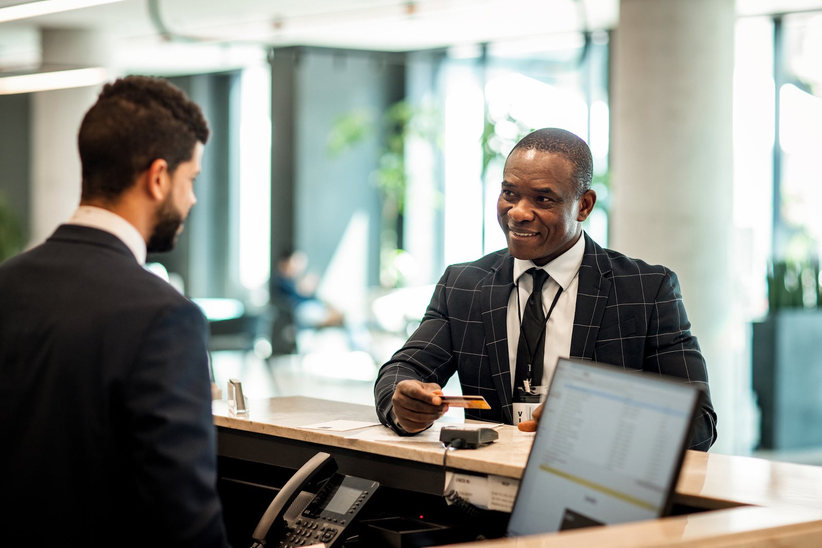 a man in a suit pays with a credit card at a hotel front desk