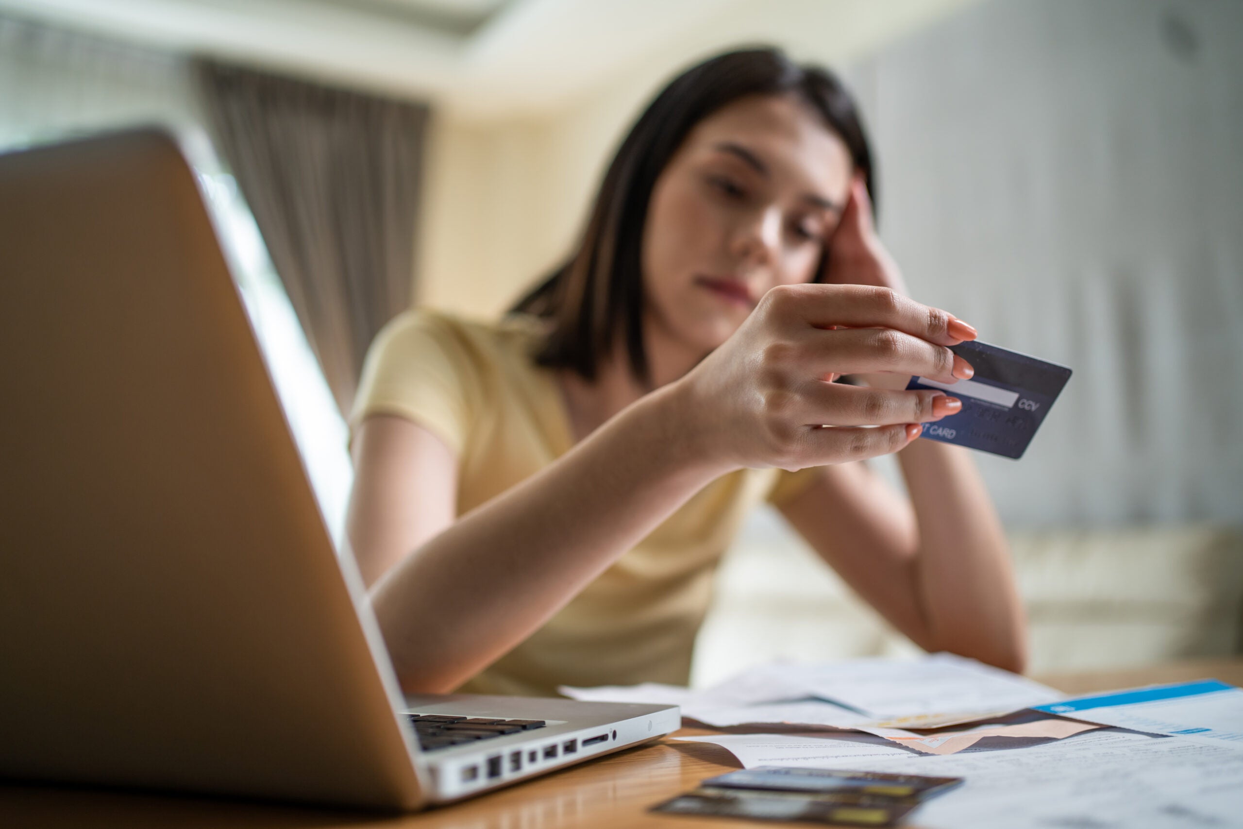 Woman looks distressed at credit card