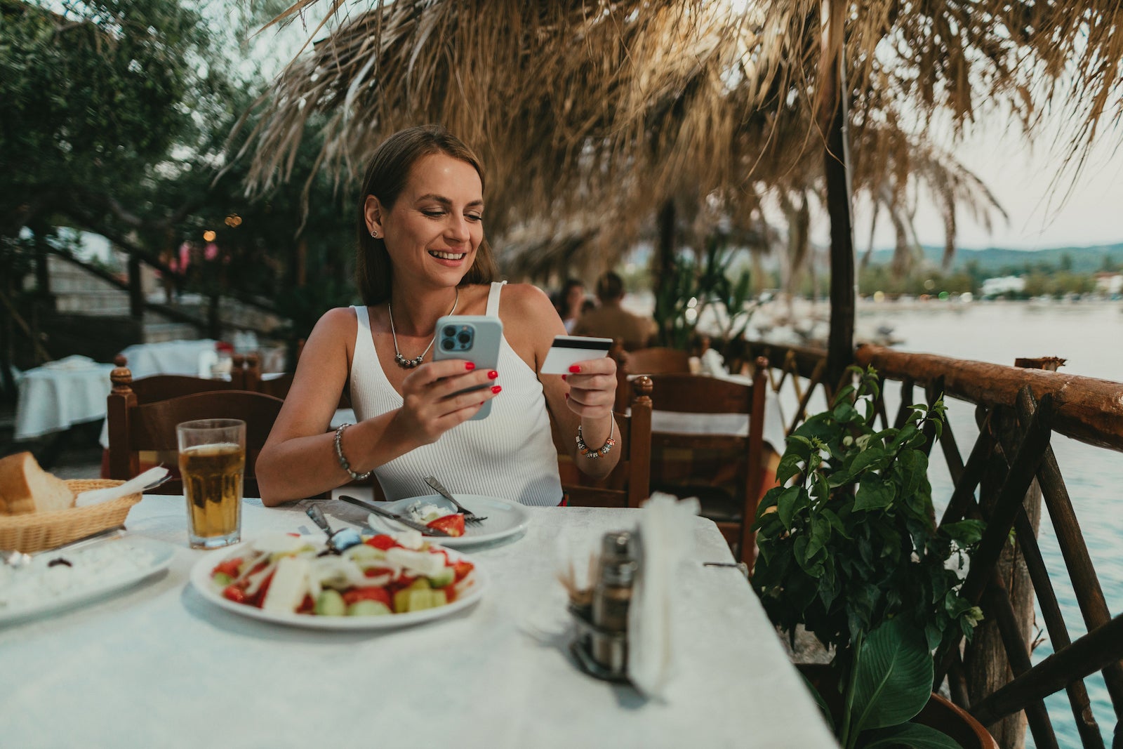 a young woman pays with a credit card at an outdoor restaurant in a tropical location