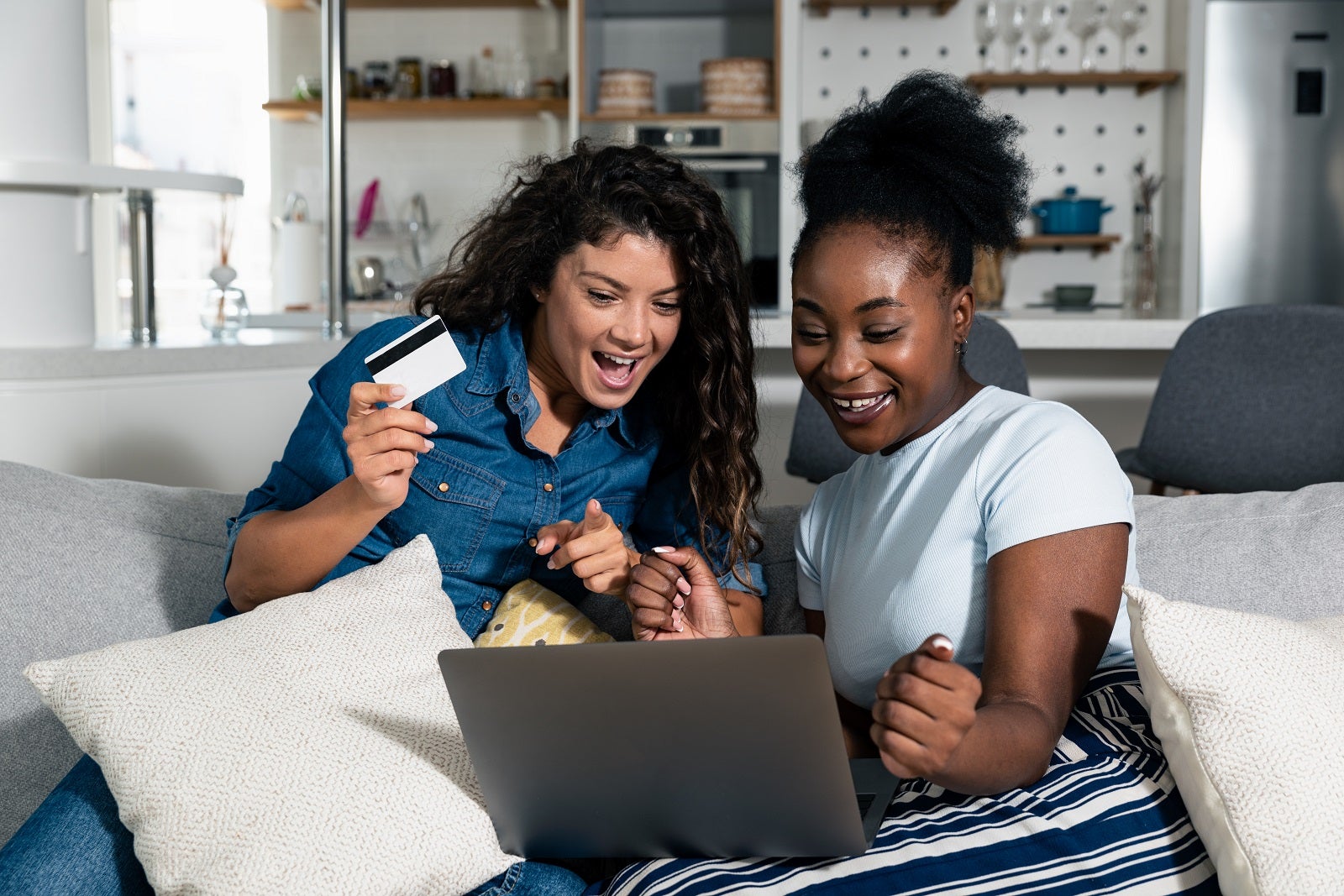 two women on on a sofa looking at a laptop