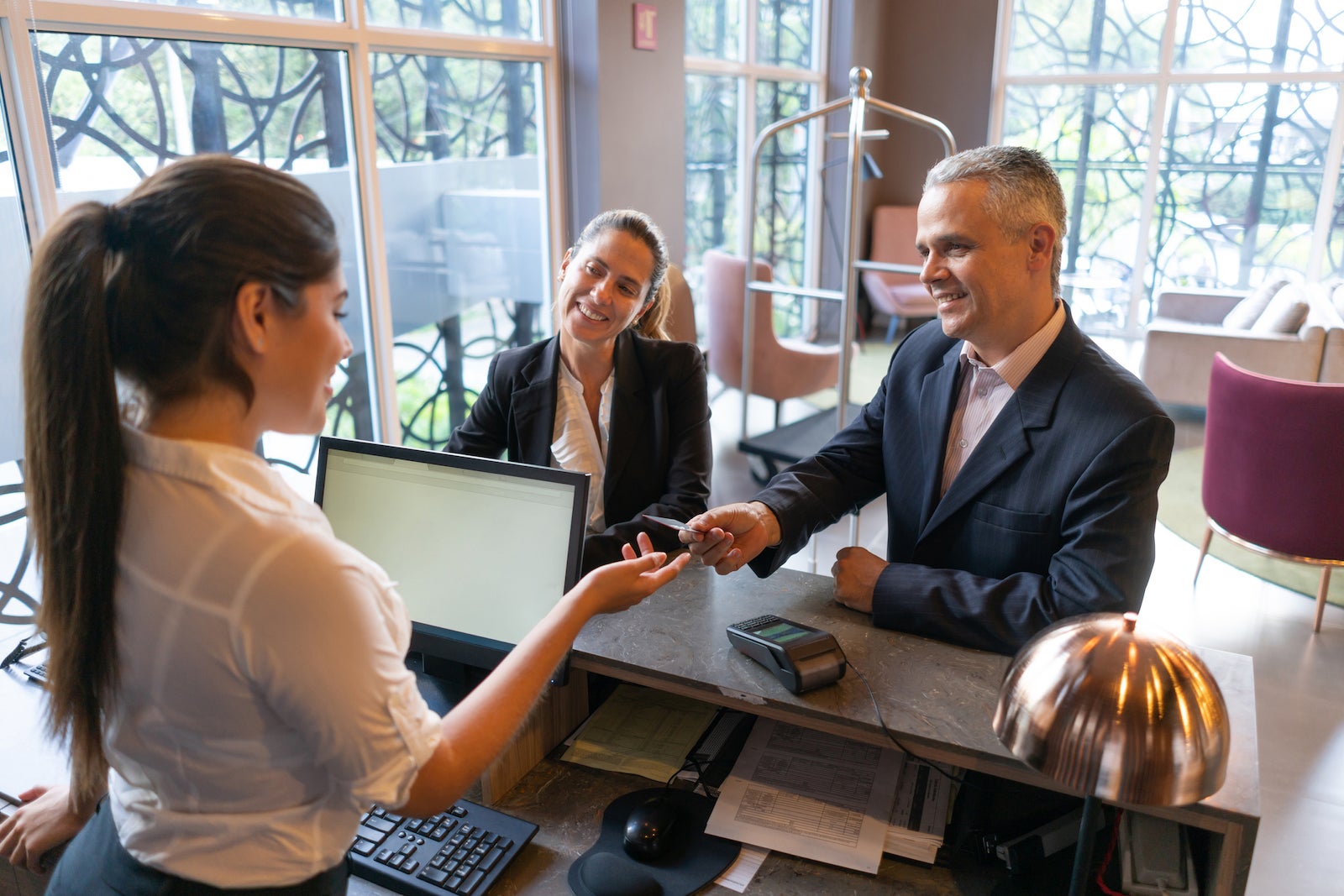 a couple pays with a credit card at a hotel front desk