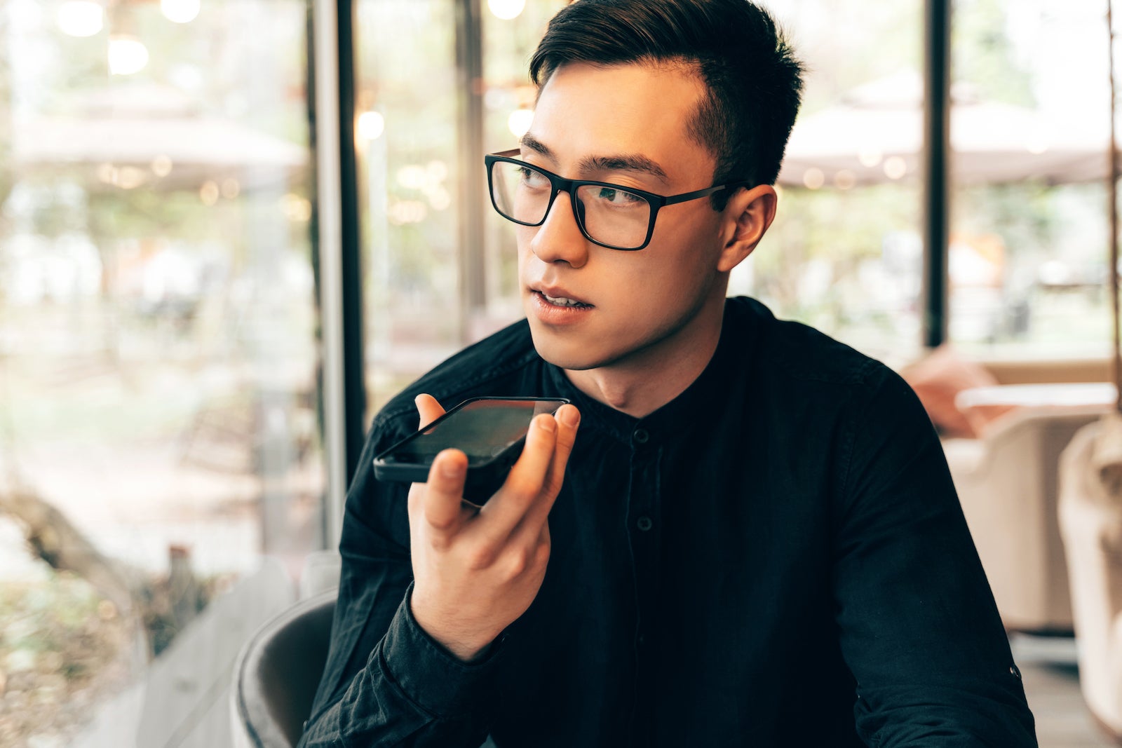 a young person with glasses uses speaker phone during a phone call