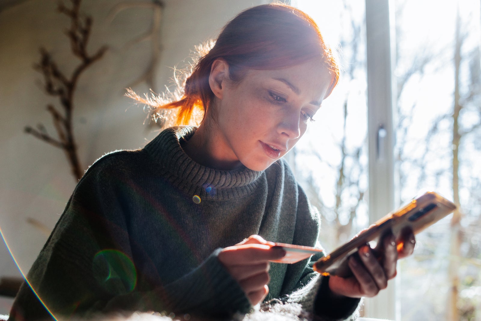 a young woman holds a credit card while making a phone call