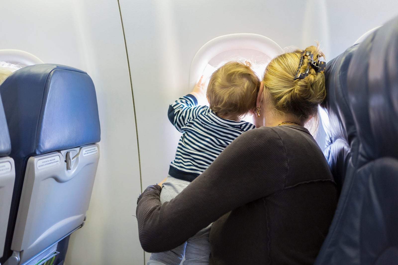 A woman holding a child looking out of an airplane window