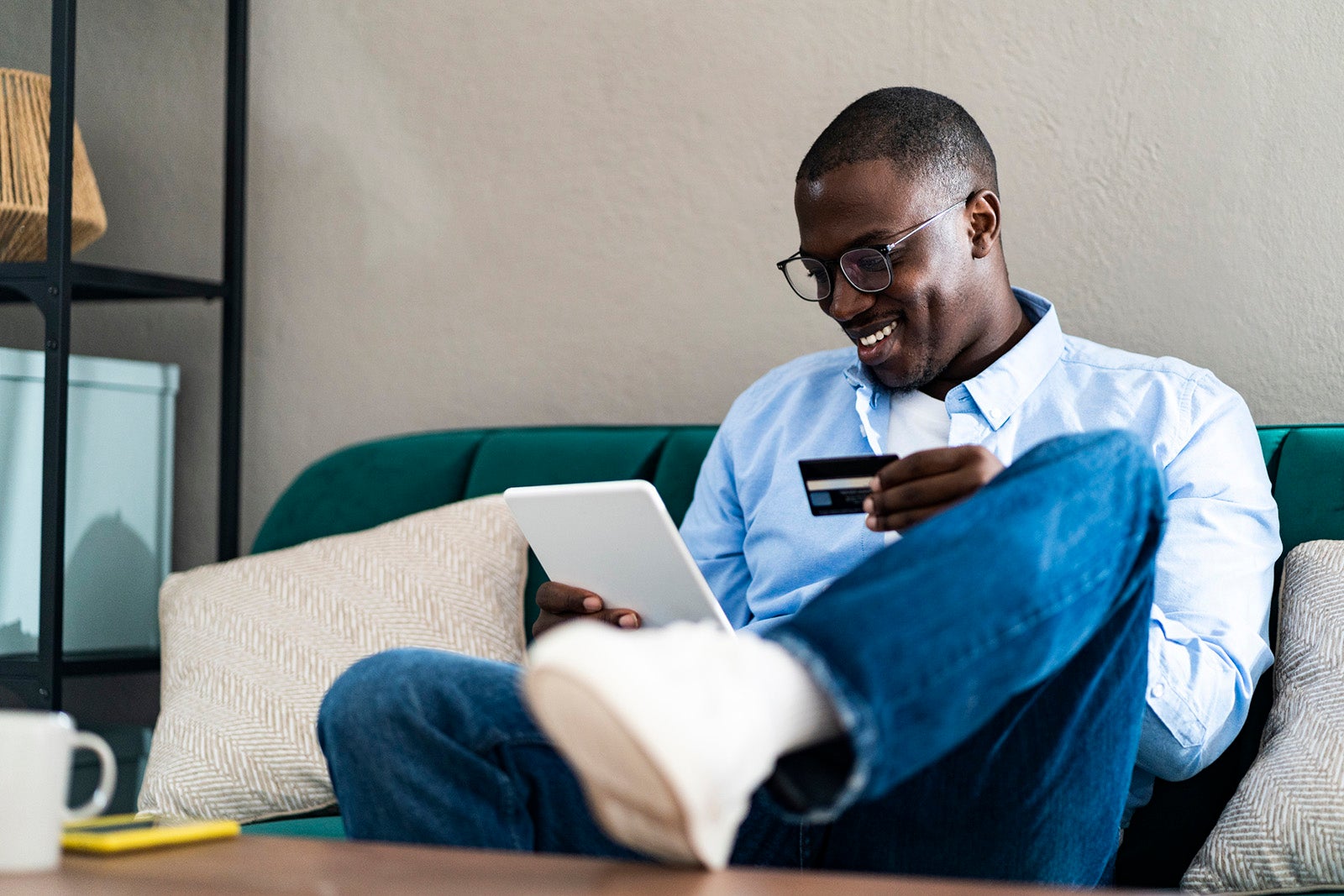 Smiling man paying through credit card while using digital tablet at home